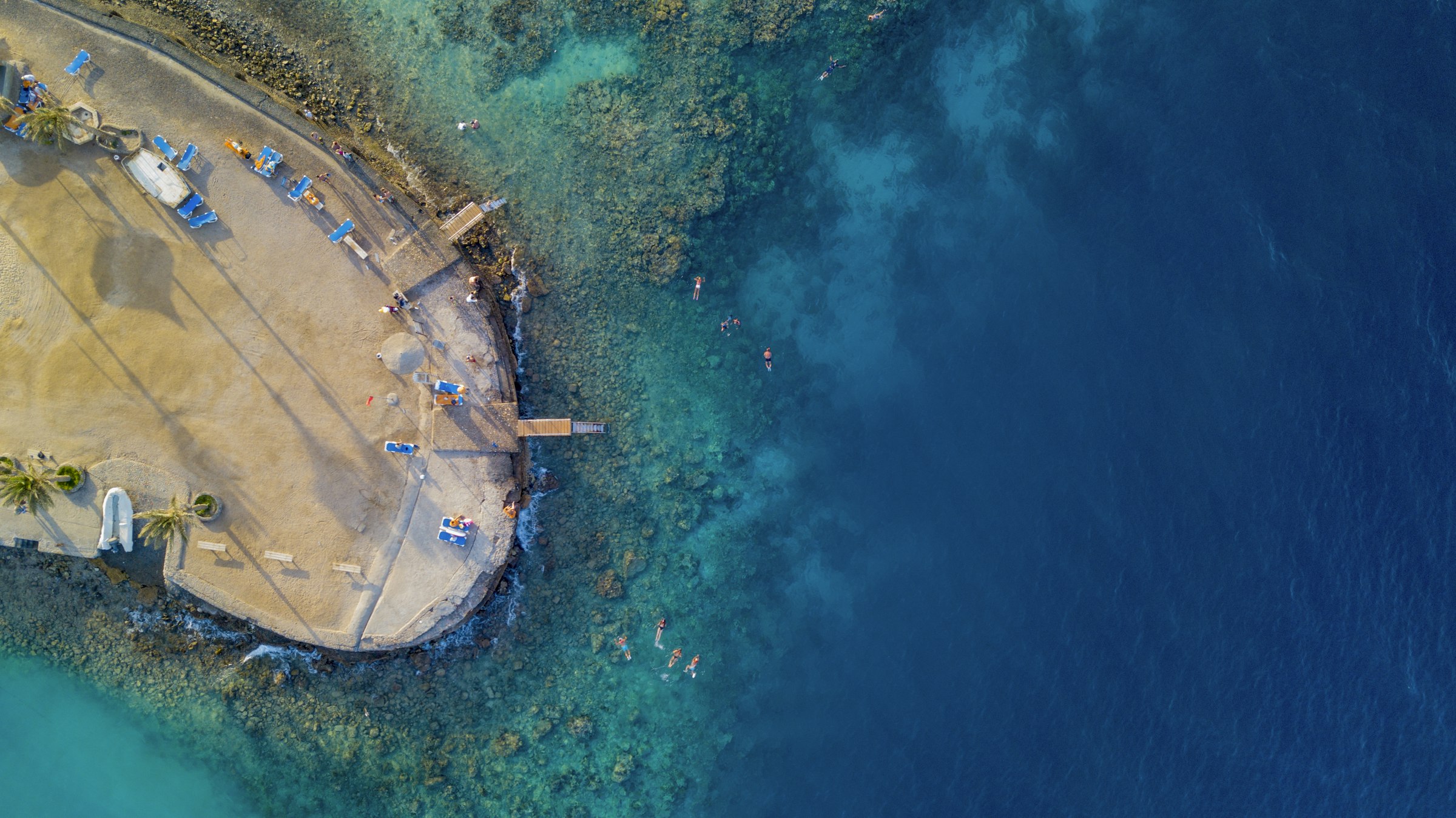 A boat on the clear turquoise water of the Red Sea seen from above